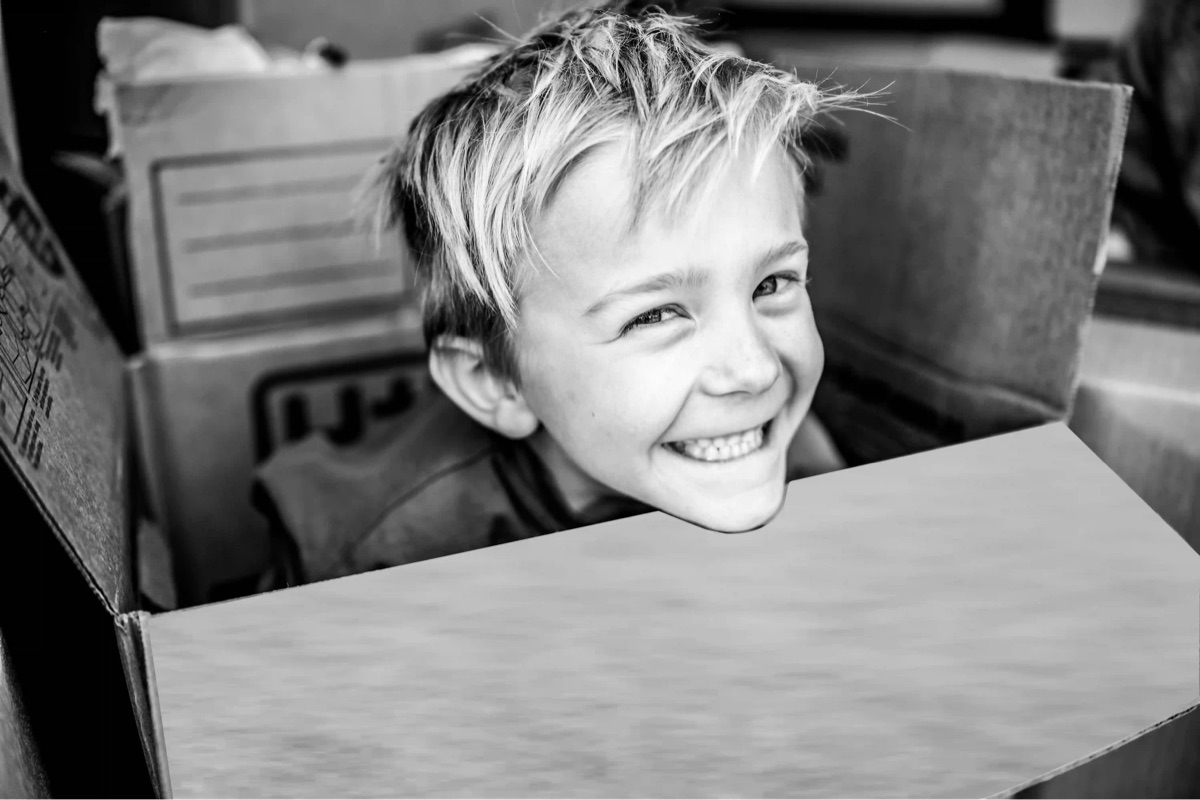 Joyful child popping from a moving box — the calm only a licensed carrier delivers